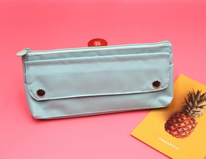 Detailed close-up of mint green canvas pencil case with snap pocket on pink background