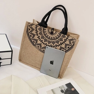 Detailed shot of ethnic linen tote bag with black geometric print next to an iPad for scale