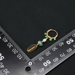 Long drop earrings with green beads, white pearl and gold handmade charm on black background