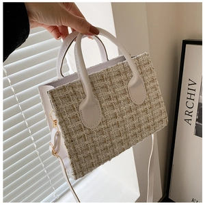 Detail of beige tweed woven handbag with white leather handle and adjustable shoulder strap