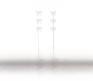 Macro detail of copper bow tassel earrings with crystals and a white pearl bead