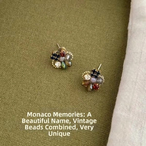 Close-up of vintage multi-color flower stud earrings on dark green textured linen