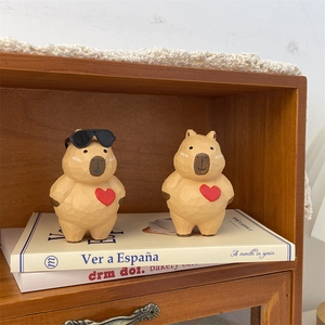 Detail of hand-carved Capybara figurines with red hearts and mini sunglasses