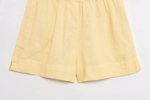 Détail de short en coton et lin jaune clair montrant la texture respirante et les coutures