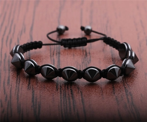 Macro shot of punk black beaded bracelet featuring metal cone charms and adjustable cord