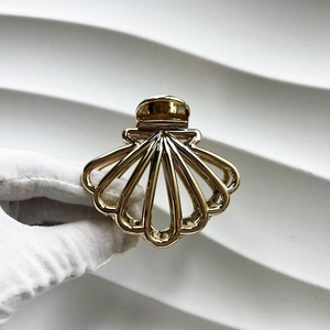 Close-up of a gold-plated scalloped hair claw clip with a hollow shell design