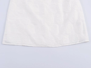 Detailed macro view of white elegant fabric texture with circular floral embroidery on the hem