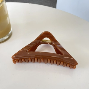 Detail of 12cm brown triangle hair claw clip with gold spring on white background