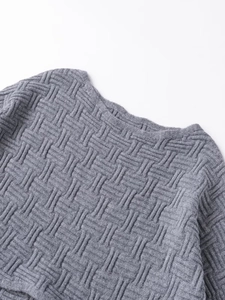 Detailed macro view of the grey knit sweater showing premium cross-weave texture and fiber