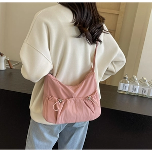 Detail of pink nylon crossbody bag featuring unique drawstring pleats and textured fabric