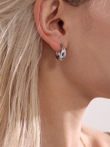 Gros plan de boucles d'oreilles créoles argentées épaisses portées par un mannequin