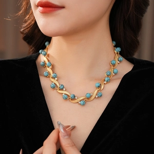 Close-up of vintage gold necklace with turquoise beads and inlaid crystals on a model