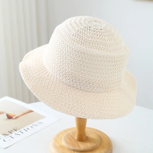 Beige knit bucket hat for women featuring intricate crochet texture on a wooden stand
