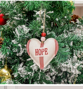 Close-up of heart-shaped linen Christmas ornament with red stripes and wood beads