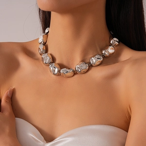Detailed close-up of a chunky silver irregular liquid metal chain necklace on a model