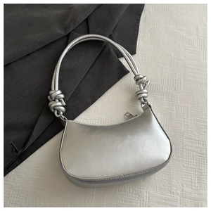Detail of silver metallic crescent bag with unique knot shoulder strap design