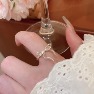 Silver bow ring with stones shown on model finger in a delicate lifestyle setting