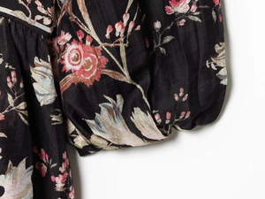 Detailed close-up of retro floral pattern fabric and puff sleeve tailoring of the dress