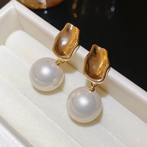 Detail showing high-lustre round white pearls with gold textured metal drop earrings