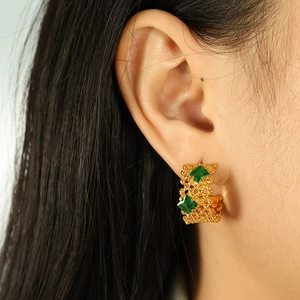 Boucles d'oreilles grillagées en or 18K avec zircons verts portées par un mannequin