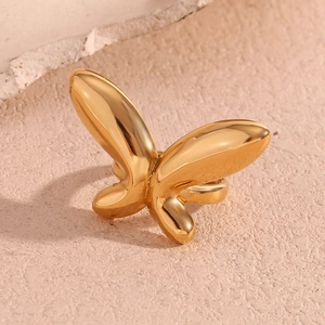 Gros plan d'une bague papillon plaquée or 18 carats sur un fond en pierre texturée