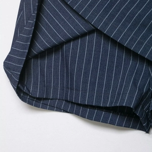 Close-up of navy blue pinstripe pleated skirt hem with detailed woven fabric texture