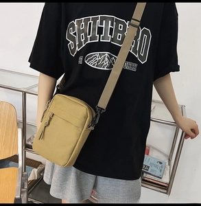 Detailed view of khaki nylon crossbody bag with adjustable strap and front zipper pocket