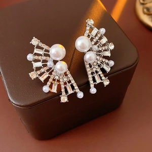 Macro shot of silver fan-shaped earrings with sparkling crystals and white pearls