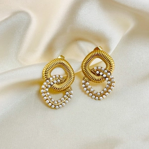 Detailed close-up of vintage gold pearl earrings on smooth yellow silk background