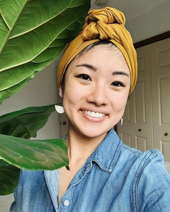 Detail eines senfgelben verknoteten Baumwollturbans, getragen von einer Frau im Innenraum