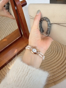 Close-up of pearl strap watch with rose gold oval dial and white mother of pearl face