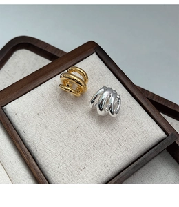 Macro detail of multi-layer gold and silver ear cuffs on a minimalist linen display