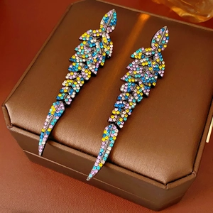 Détail de boucles d'oreilles vintage en forme de feuille avec strass colorés sur cuir brun