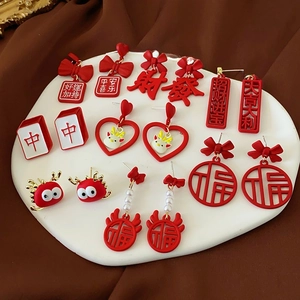 Red festive tassel earrings with traditional Chinese good luck charms on white ceramic plate