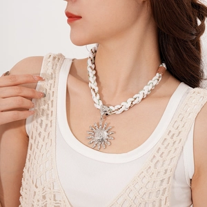Detail of bohemian sun pendant necklace with woven cotton rope on model neck