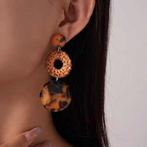 Close-up of leopard resin earrings with woven rattan rings on model in retro style
