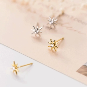 Macro shot of gold and silver eight-pointed star stud earrings with zircon crystals