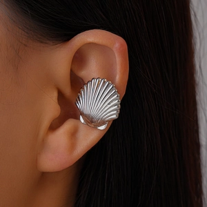 Detail showing shell-shaped silver ear cuff with textured metal pattern on a female ear