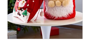 Détail d'un sac cadeau Père Noël en velours rouge avec barbe en peluche et pompons blancs