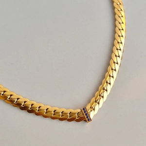 Close-up of gold 18k plated chain necklace featuring rectangular blue zircon stone settings