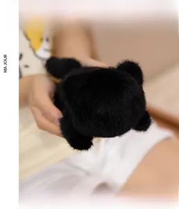 Close-up of a mini black plush cat magnet with yellow eyes held in hand