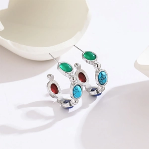 Detailed view of silver C-shaped earrings with colorful oval gemstone inlays