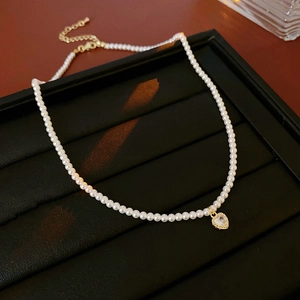 Gros plan du collier de perles avec pendentif cœur doré et zircon sur fond de velours