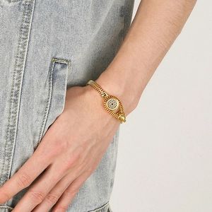 Detail of a gold titanium zipper bracelet with red accents worn by a male model