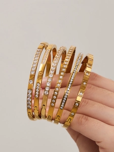 Vista dettagliata di 6 bracciali rigidi sovrapposti in acciaio inossidabile placcato oro 18k