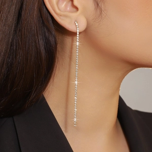 Close-up of model wearing gold tassel earrings with sparkling rhinestones in a sleek design