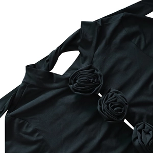 Détail de robe noire à manches longues avec découpes et décorations de roses 3D