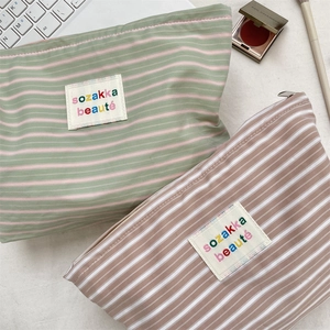 Flat lay of green and brown striped canvas cosmetic bags with colorful logo detail