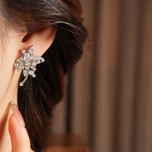 Detail of silver star earrings with zircons shown on ear for realistic size and sparkle