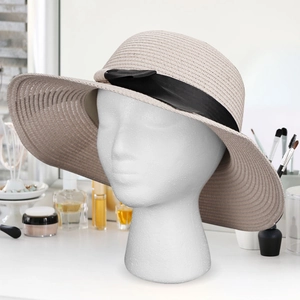 Detail of a beige woven straw sun hat with black ribbon on a foam mannequin head